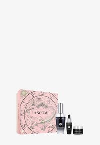 Set de soins Lancome Génifique dans une boîte décorative rose avec un design de horloge, comprenant un sérum, un sérum contour des yeux et une crème dans des contenants élégants.
