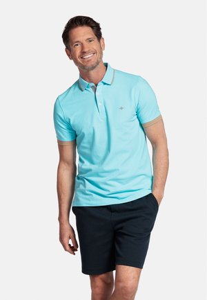 Polo léger bleu clair à manches courtes avec un col beige contrastant, associé à un short bleu marine foncé. Le tissu semble lisse et léger.