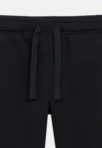 Črne bombažne trenirke z vrvico v pasu, gladkim teksturom in minimalističnim dizajnom. Poudarek na udobju in enostavnosti nošenja.