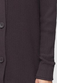 Strickjacke in Dunkellila, mit einem strukturierten Stoff, Knopfverschluss und gerippten Bündchen. Weiches, warmes Material mit einem schlichten Design.