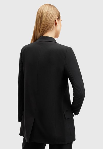 Blazer noir avec une coupe ajustée, fente arrière simple et revers cranté. Fabriqué dans un tissu lisse avec des manches longues et des poches latérales.