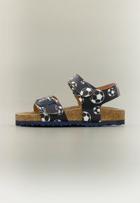 Παιδικό μπλε σαγιονάρι με λευκό σχέδιο ποδοσφαιρικής μπάλας, πάτο από φελλό, δύο ρυθμιζόμενα λουριά με αγκράφες και μπλε καουτσούκ σόλα.