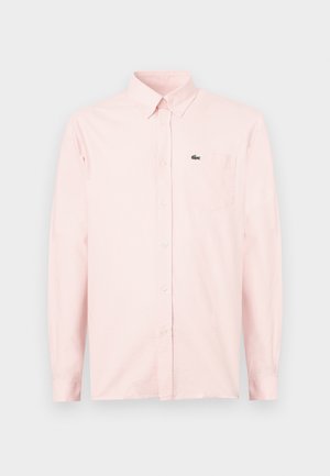 Chemise rose clair à manches longues avec boutons, poche poitrine et petit logo de crocodile vert sur la poche.
