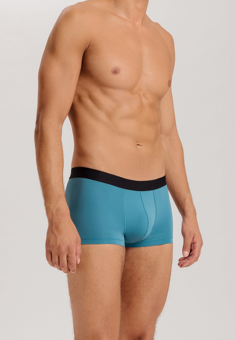 Blå boxershorts med svart midjeband, tillverkade av ett mjukt och stretchigt tyg, med en figurnära design och kontrasterande sömmar.