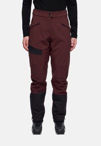 Heren skibroek in donker bordeauxrood met zwarte accenten. Voorzien van een knoopsluiting, ritszakken en taps toelopende pijpen. Gemaakt van duurzaam materiaal.