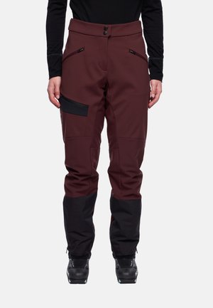 Heren skibroek in donker bordeauxrood met zwarte accenten. Voorzien van een knoopsluiting, ritszakken en taps toelopende pijpen. Gemaakt van duurzaam materiaal.