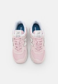 Paire de baskets New Balance Classic 574 roses avec des accents blancs et des semelles intérieures bleues, vues de dessus sur fond blanc.