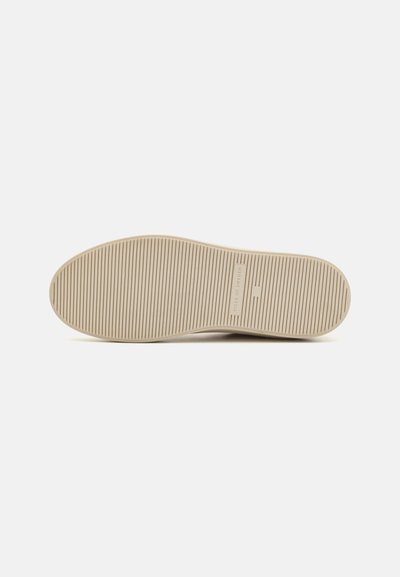 Beige rubber shoe sole with horizontal ridges, featuring a logo print in the center. The design is flat and oval-shaped.
