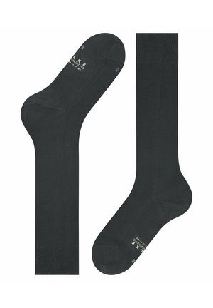 Dwie czarne, sięgające do kolan skarpetki rozłożone na płasko, jedna pokazująca górę z dzianym mankietem, druga spodem z białym nadrukiem i oznaczeniami rozmiaru.