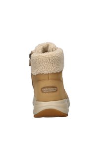 Botas impermeables marrones con un suave cuello crema, costuras pronunciadas y una suela ligera. Cuentan con una cremallera lateral para ponérselas fácilmente.