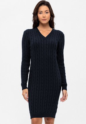 Vestido de punto azul marino con cuello en V, mangas largas y puños y dobladillo acanalados. Confeccionado en un tejido de punto texturizado. Silueta ajustada.