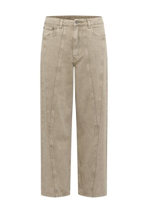 Pantalons larges beige en tissu doux et texturé, avec des coutures marquées et une coupe droite. Ils possèdent une fermeture à bouton et à glissière.