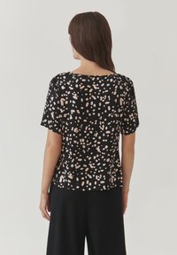 Top nero a maniche corte con un motivo maculato in crema e rosa chiaro, con scollatura rotonda e vestibilità comoda. Tessuto liscio.