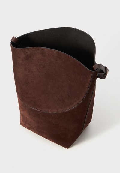 Brown suede tote bag with smooth texture, curved top edge, and leather strap. Open interior with no visible hardware or embellishments.