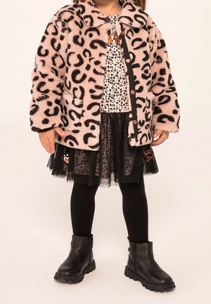 Rosa leopard mønster faux fur jakke, sort og hvid prikket bluse, sort tyl nederdel, sorte leggings og sorte ankelstøvler med teksturerede såler.