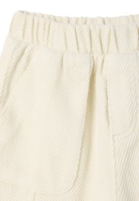 Lesbian beige textured fabric with a ribbed waistband and side pockets, showcasing a herringbone pattern and soft surface.