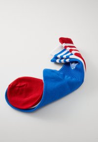 Kniehoge sokken in de kleuren rood, wit en blauw. Strepen en effen oppervlakken creëren een gedurfde patroon met een zachte, gebreide textuur.