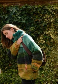 Pull en polaire dans des teintes bleu-vert et terreuses, avec un col montant et une coupe oversize. Texture douce avec un motif dégradé.