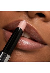 Balsam do ust o błyszczącym, jasnoróżowym wykończeniu, na pełnych, nawilżonych ustach. Czarna tubka z srebrnymi akcentami.