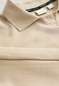 Béžová bavlnená polo košeľa s textúrovaným golierom a štítkom s logom "Ted Baker". Hladká tkanina s čistým, sklopeným dizajnom.