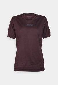 Camiseta atlética de manga corta en color burdeos con cuello redondo, elaborada en tejido ligero, que presenta un sutil logo "TERREX" en azul en la parte delantera.