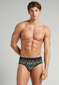 Męskie slipy z czarnym tłem oraz wzorem nawiązującym do Grincha w kolorach zielonym i czerwonym. Miękki materiał, elastyczny pasek w talii i dopasowany krój.