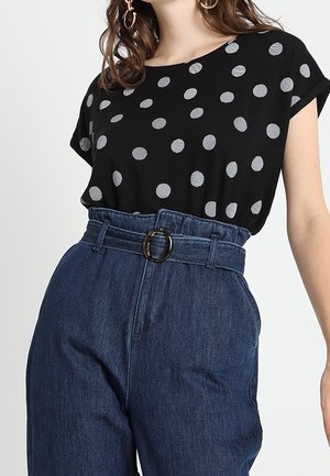 Czarny top z krótkim rękawem w białe paseczki w kropki, połączony z niebieskimi dżinsowymi spodniami z wysokim stanem, zdobionymi paskiem z okrągłą klamrą.