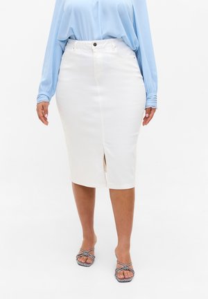 Kobieta ubrana w białą ołówkową spódnicę do kolan z przednim rozcięciem, w połączeniu z jasnoniebieską bluzką z długim rękawem i czarno-białymi sandałami na paseczki.