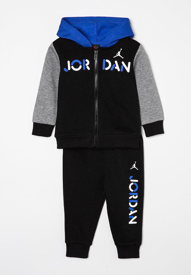Chándal negro con mangas grises y capucha azul. Presenta el texto y logo en blanco "JORDAN". Fabricado en tejido suave con cremallera frontal y puños elásticos.