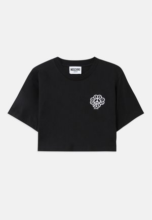 T-shirt preta cropped feita de algodão, com um gráfico de símbolo da paz floral branco no lado esquerdo do peito. Mangas curtas e um design de gola redonda.