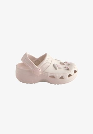 Lichtroze unisex klomp met verstelbare achterriem en decoratieve bedeltjes bovenop, met ventilatiegaten langs de zool.