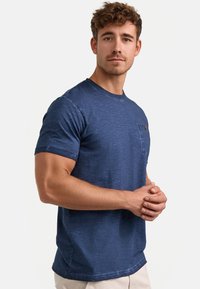 Marineblå kortærmet T-shirt i tekstureret bomuld, med en brystlomme og rund halsudskæring. Casual pasform med en glat overflade.