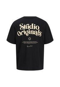 Černé tričko s krátkým rukávem s velkým krémovým textem "Studio Originals" na zádech, s dalšími brandingovými a textovými detaily pod ním.