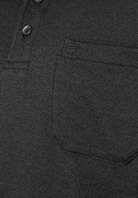 Sort polo-shirt i tekstureret stof med en treknaps placket og en lille brystlomme med en subtil logo-detail.