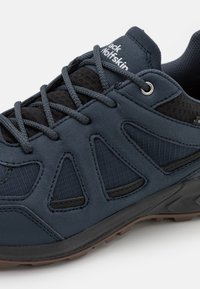 Scarpa da trekking blu scuro con accenti in mesh, dotata di lacci robusti, suola ammortizzata e trazione in gomma sul fondo per migliorare la presa.