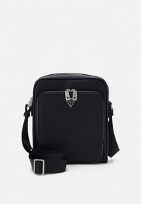 Black synthetic crossbody bag with a square shape, silver hardware, front zipper pocket, and adjustable strap. Features a logo detail.