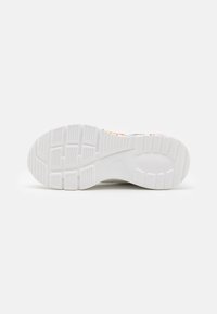 Schuhsohle mit einer strukturierten weißen Gummifläche und tiefen Rillen sowie Mustern für Traktion und Stabilität. Sichtbare Akzente eines farbenfrohen Designs.