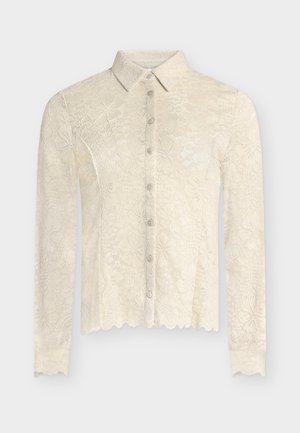 Krémová krajková halenka s dlouhým rukávem, ozdobená vroubkovanými okraji, knoflíky vpředu a klasickým límečkem, zdobená květinovým krajkovým vzorem po celém povrchu.