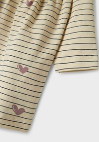 Camisa de manga corta a rayas en suave tela amarilla con rayas horizontales negras; presenta un estampado de corazones rosas en la manga.
