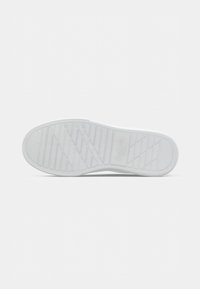 Talpa de adidași albi cu modele texturate pentru aderență și logo-ul mărcii embossat aproape de centru, pe un fundal alb simplu.