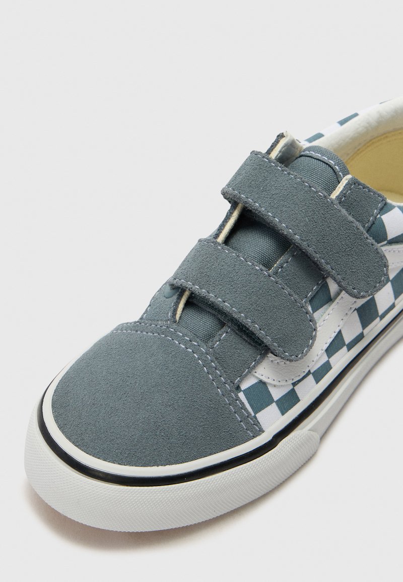 Graue Wildleder-Sneaker mit blauem und weißem Karomuster, Klettverschluss, abgerundeter Spitze und weißer Gummisohle mit schwarzem Rand.