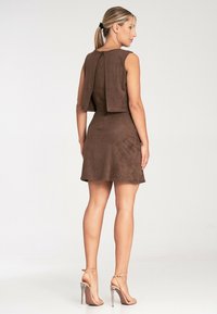 Braunes Wildlederkleid mit einer kurzen oberen Schicht, tailliertem Schnitt und ausgestellt Rock. Verfügt über einen Reißverschluss auf der Rückseite und hochhackige Sandalen.