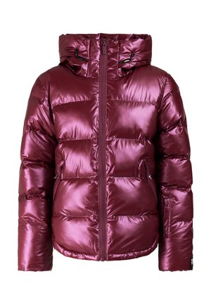 Jonge vrouw staat in een glanzend paarse pufferjas, paarse broek, zwarte handschoenen en laarzen en een roze gebreide muts.