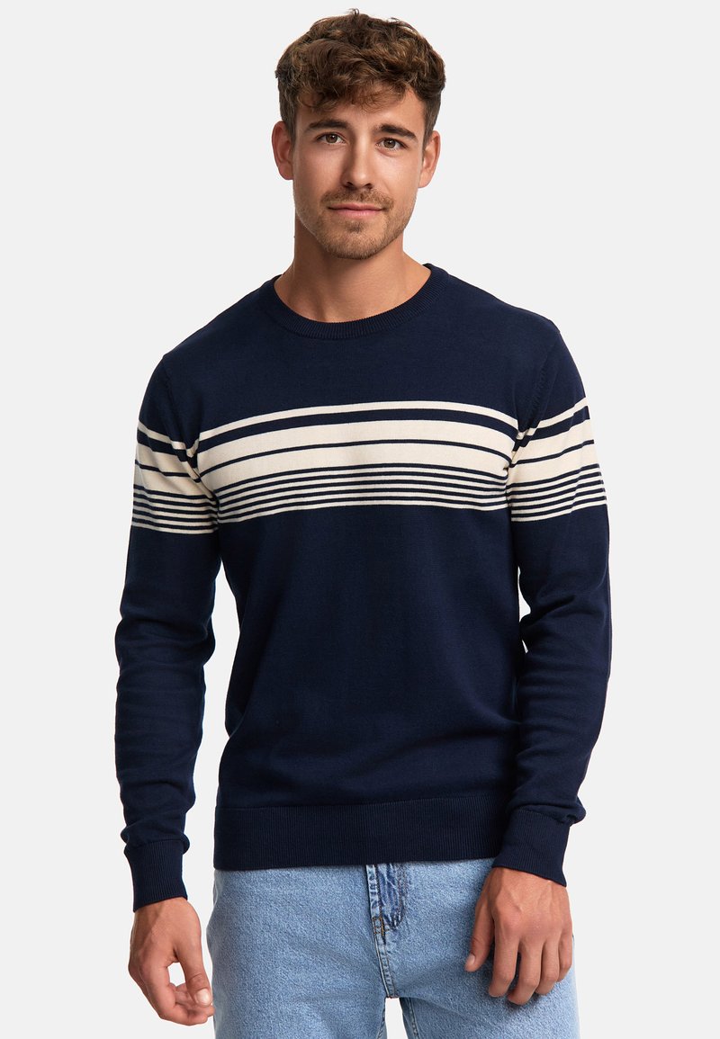 Pull bleu marine avec des rayures horizontales crème et bleu foncé sur la poitrine, encolure ronde et poignets côtelés. Texture tricot doux.