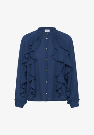 Blusa azul marino con cuello mandarín, delantero con botones y grandes volantes en cascada en la parte delantera. Presenta botones en tono dorado y mangas fruncidas.