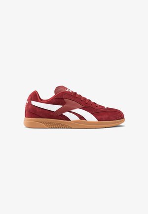 Zapatillas deportivas de ante rojo con acentos blancos y rayas distintivas. Cuentan con una suela de goma y un tejido texturizado, diseñado para la comodidad y el soporte.