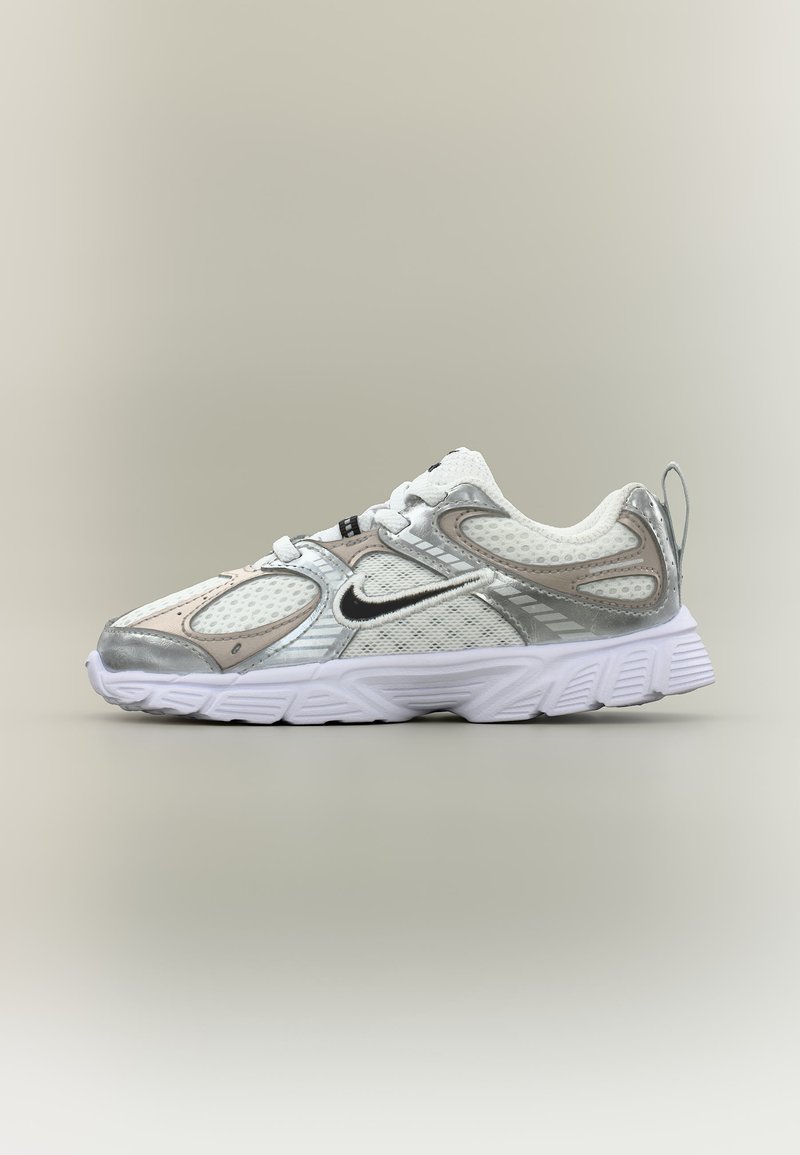 Άσπρο και ασημί αθλητικό παπούτσι Nike με διχτυωτές επιφάνειες, μαύρο σήμα Swoosh και παχιά υφασμένη σόλα, εμφανίζεται σε πλάγια όψη σε ουδέτερο φόντο.