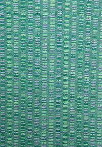 Woven textile w odcieniach zieleni z wzorami w zygzaki. Posiada naprzemienne paski jasnej i ciemnej zieleni z niebieskimi akcentami, teksturowany materiał.