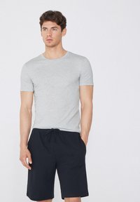 Camiseta de algodón gris de manga corta combinada con pantalones cortos azul marino con cordón, que cuentan con bolsillos laterales y un ajuste relajado.