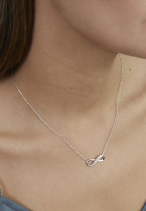 Silberne Halskette mit einem Unendlichkeitssymbol, das mit kleinen klaren Steinen verziert ist. Die Kette ist zart und schlicht gestaltet.
